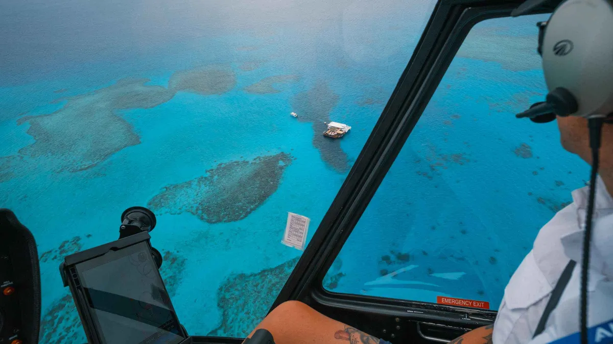 View from a helicopter cockpit over turquoise reef and islands on a scenic Mamanuca Islands tour from Denarau, Fiji