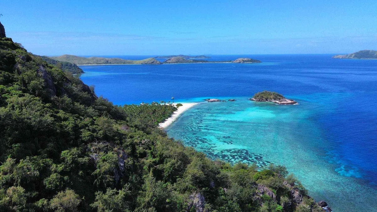 Aerial view of a coral-fringed island and sand spit in the Mamanuca Islands, the archipelago covered by Mamanuca Islands tours from Nadi