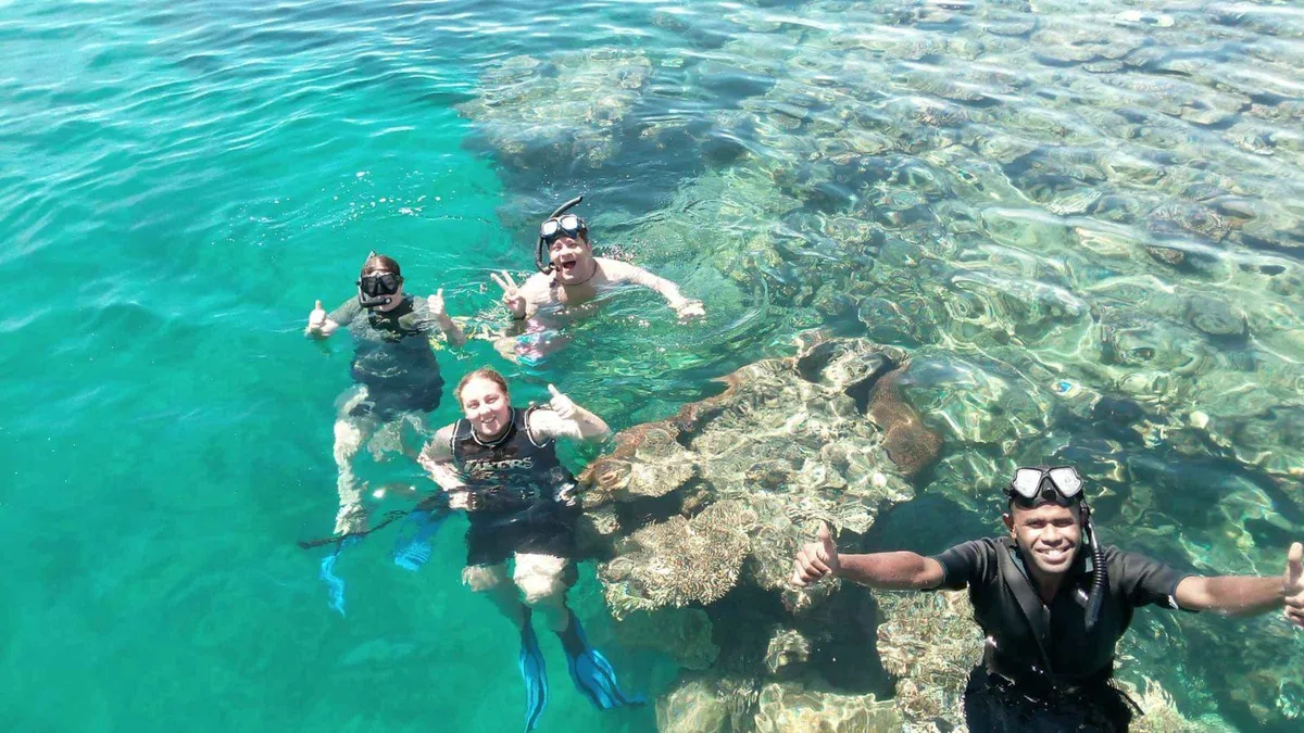 Snorkellers in clear shallow water above coral on a Mamanuca Islands tour to the Treasure Island turtle sanctuary in Fiji