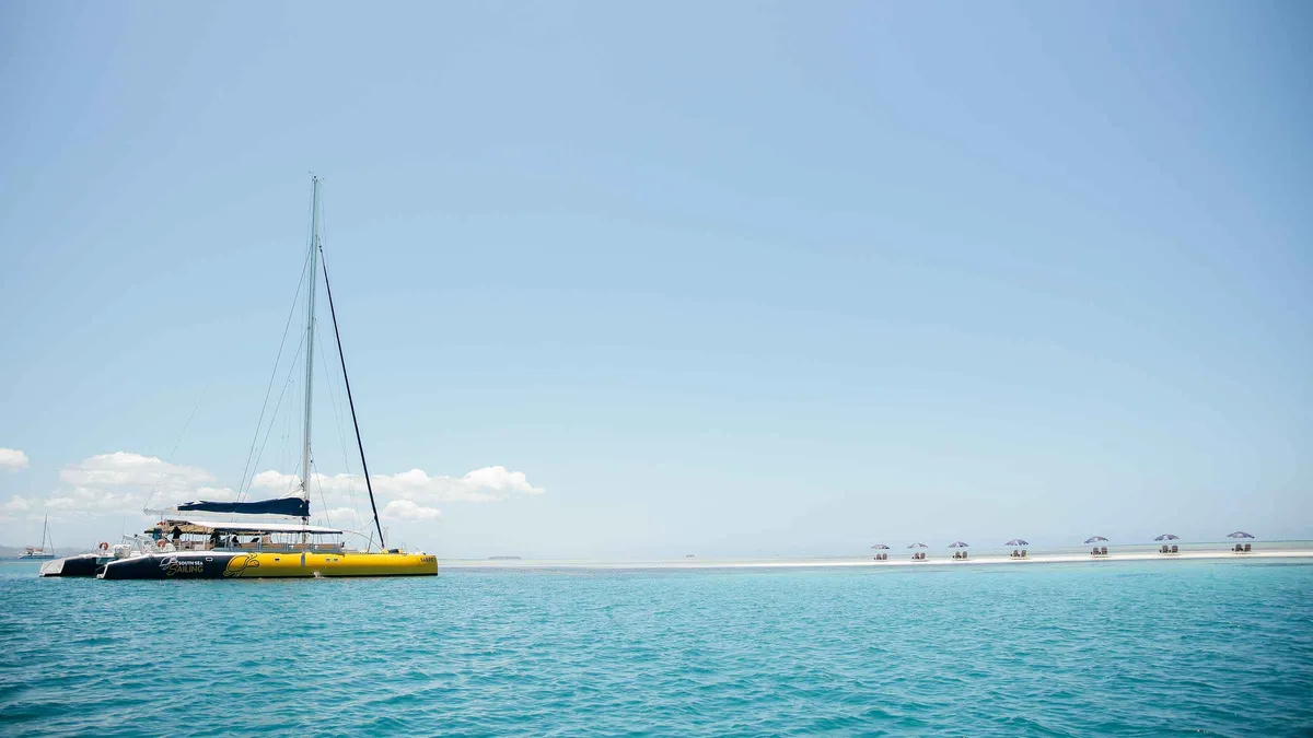 Guests on the yellow Sabre sailing catamaran during a Mamanuca Islands tour to a private sand cay in Fiji
